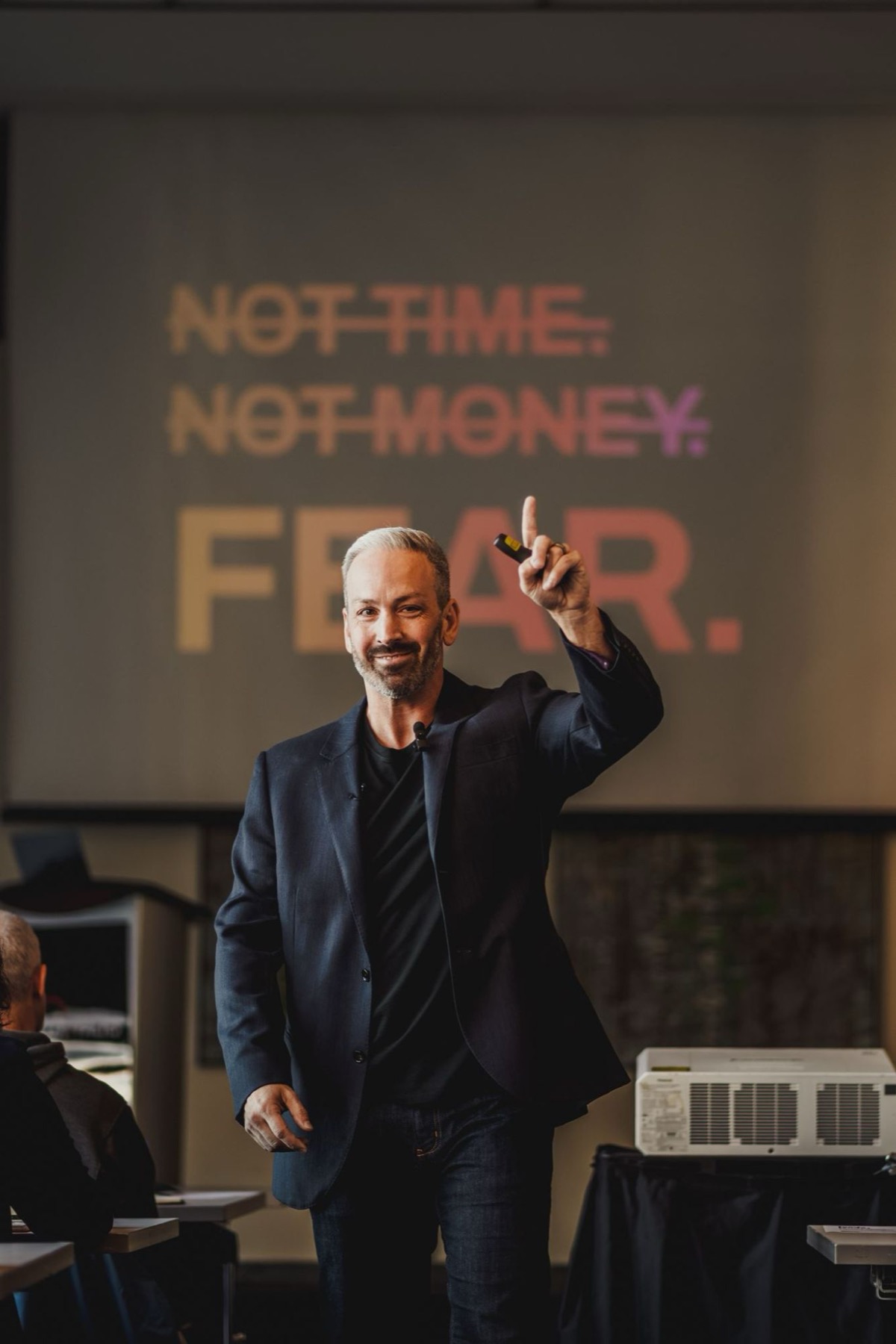 Alain Desaulniers on stage in front of a slide reading: Not time. Not money. Fear.